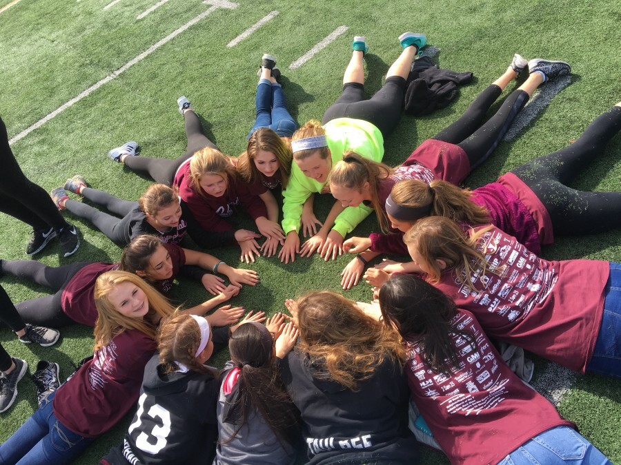 a group of students laying on a field of grass in a circle
