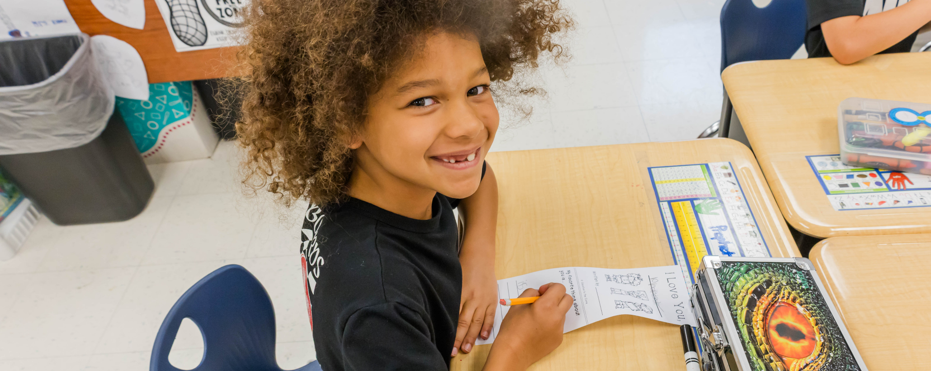 school aged boy at a desk smiling