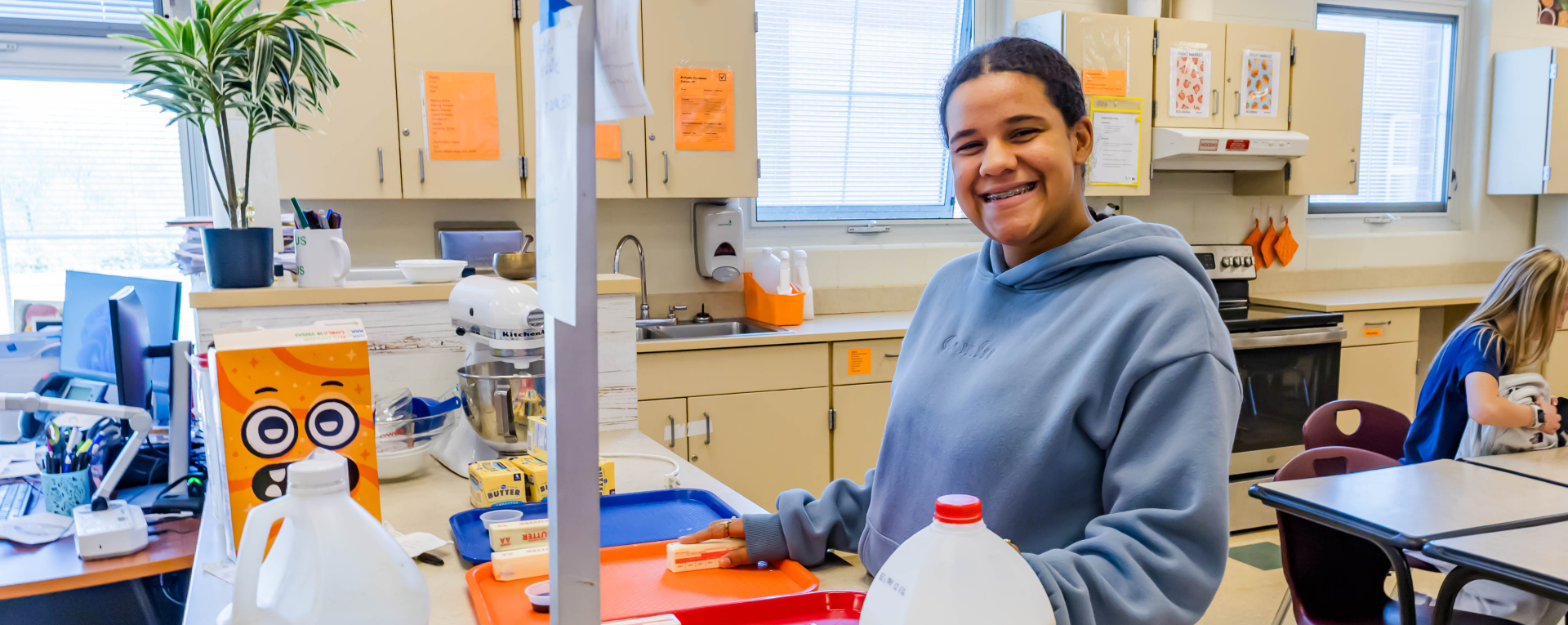 student smiling in front of a table of food items